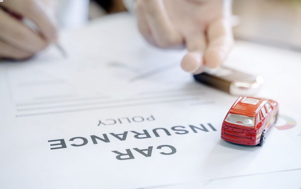 How Does Car Insurance Work in Illinois? 1 Car insurance policy with red car toy and blur image of man hand