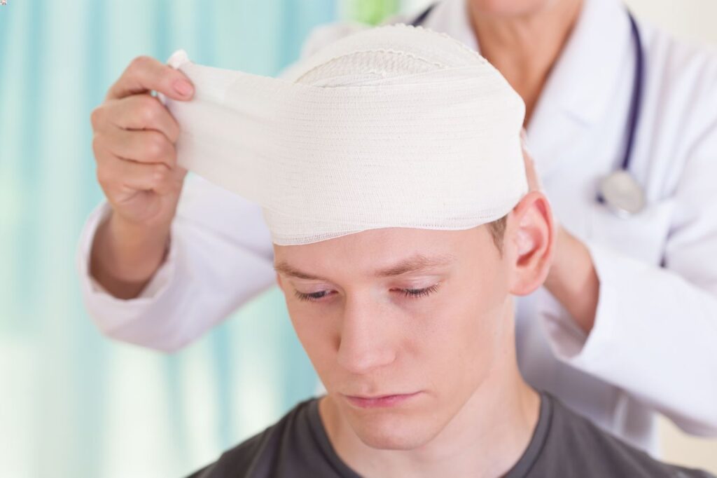 Guide to Understanding Your Loved One's Traumatic Brain Injuries 1 A doctor is removing bandage from a young man's head, brain injury